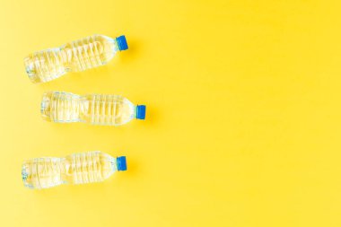 Küçük plastik şişelerde maden suyu, sarı arka planda, kopyalanmış. Üst görünüm