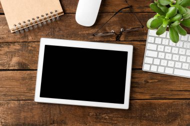 İş aksesuarları ve ahşap arka planda boş ekranı olan dijital tablet. Ofis masaüstü