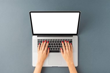 Kadın elleri laptopta çalışıyor, gri arka planda boş ekran var. Kopyalama alanı olan ofis masaüstü. Üst görünüm