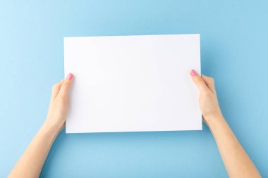 Genç kadın elleri mavi arka planda boş beyaz kağıtlar gösteriyor. Model