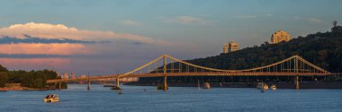 Ukrayna, Kyiv 'de gün batımında Dinyeper nehri üzerindeki yaya köprüsü.