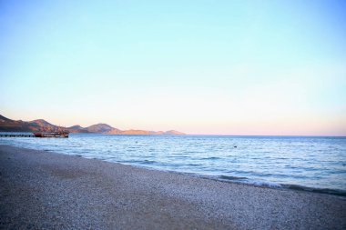 Rus bayrağı taşıyan küçük bir gemi, dağların yakınında, denizde duruyor.