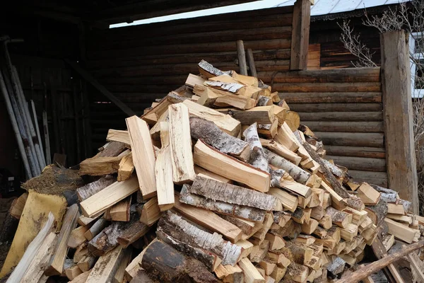 Dużo drewna na opał w pobliżu drewnianej ściany wiejskiego domu — Zdjęcie stockowe