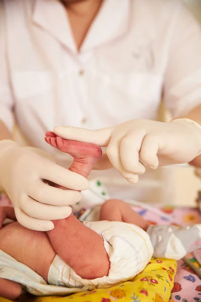 Egy fehér orvosi kesztyűt viselő orvos megvizsgál egy újszülöttet a kórteremben.. — Stock Fotó