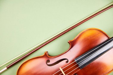 Açık yeşil arka planda keman ve yay