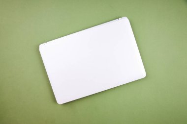 İzole edilmiş yeşil bir arkaplanda yukarıdan bilgisayarın görüntüsü kapalı. Üst görünüm.