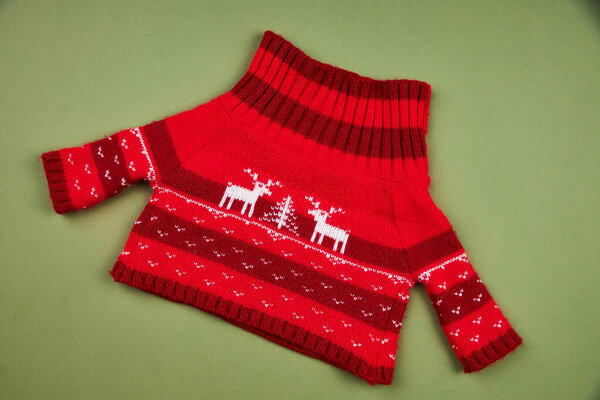 Теплый красный рождественский свитер с оленем на изолированном зеленом фоне