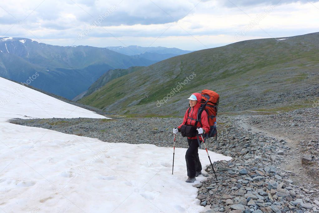 Tourist woman climbing on the snow slope of the Pass Kara-Turek, Altai Mountain, Russia