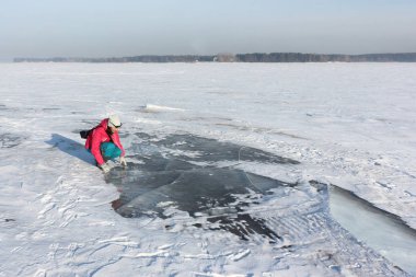 Kadın kırmızı ceketli Nehri Ob depo, Sibirya, Rusya üzerinde şeffaf buz inceliyor