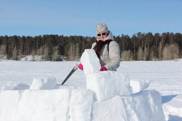 Woman in sunglasses with a saw in a hand building an igloo — 스톡 사진