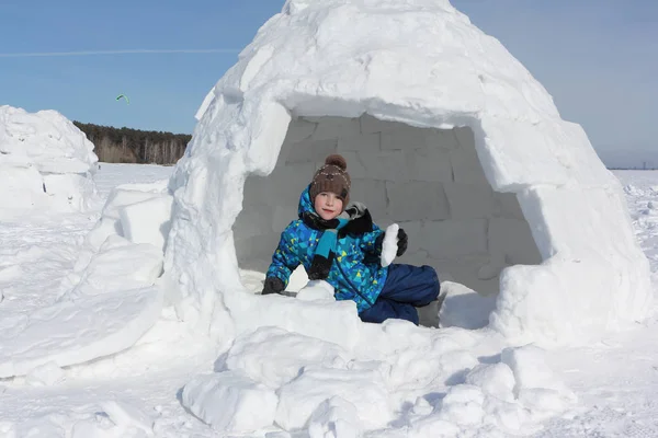 Gelukkig vrolijke jongen zittend een iglo in de winter — Stockfoto