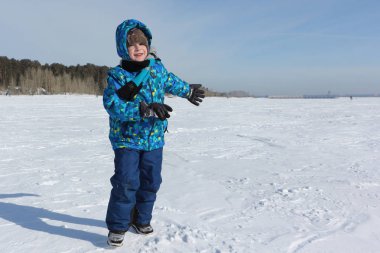 Elinde bir kartopu ile mutlu neşeli çocuk yürümeye davet ediyor 