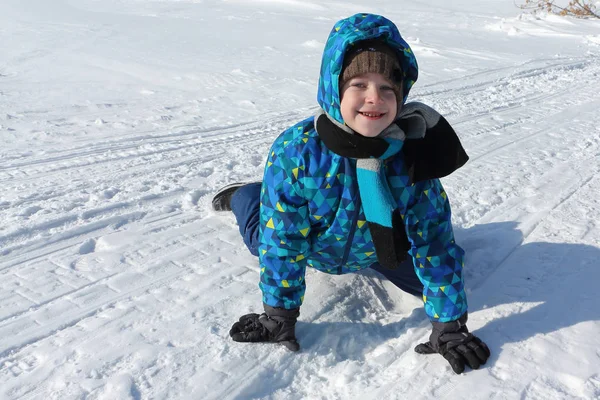Gelukkig vrolijke jongen liggend in de sneeuw in de winter — Stockfoto
