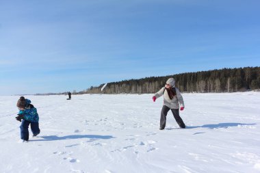 Kadın ve küçük çocuk w nehir kıyısında kartopu oynuyor