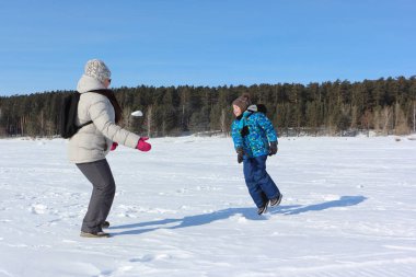 Kadın ve küçük çocuk w nehir kıyısında kartopu oynuyor