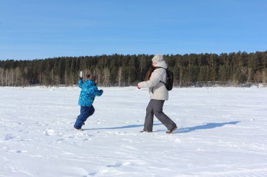 Kadın ve küçük çocuk w nehir kıyısında kartopu oynuyor