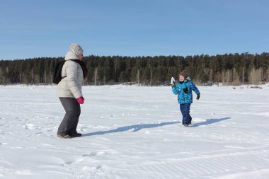 Kadın ve küçük çocuk w nehir kıyısında kartopu oynuyor