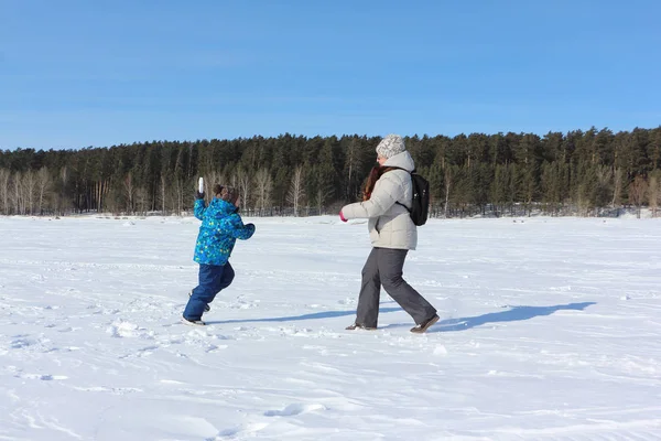 Kadın ve küçük çocuk w nehir kıyısında kartopu oynuyor