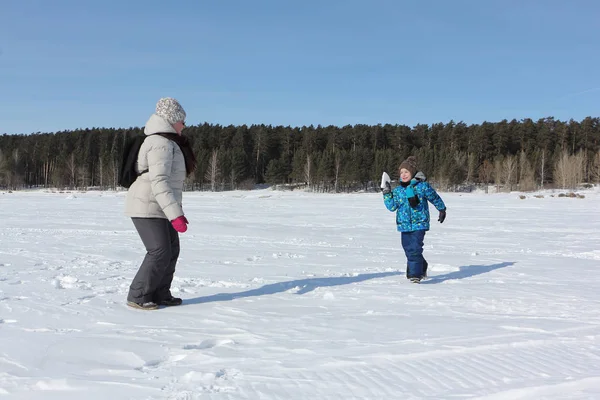 Kadın ve küçük çocuk w nehir kıyısında kartopu oynuyor