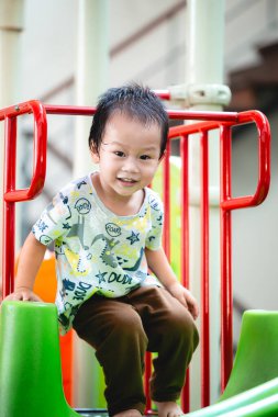 2-3 yaşındaki bir bebeğin portresi. Mutlu Asyalı çocuk oyun sahasında kas, duygusal ve zihinsel gelişimi destekleyen bir kaydırma hareketi yapıyor. Çocuk konseptini öğrenmek ve aktif olmak.