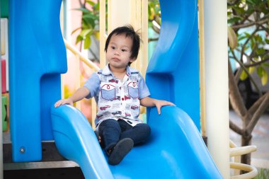 Parkta oyun parkındaki mutlu Asyalı çocuk. Neşeli küçük çocuk dışarıda etkinlik yaparken eğleniyor. 2-3 yaşlarında küçük bir oğlan..