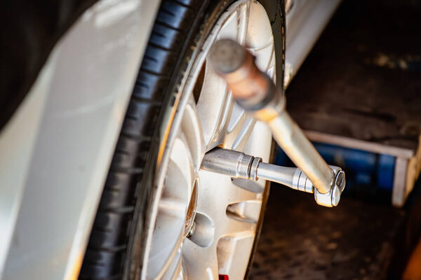 Close up of a car wheel with a torque wrench tightening the lug nuts during tire repair and maintenance in an auto workshop.