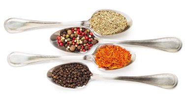 Beyaz arka plan üzerinde izole demir kaşıkları içinde farklı baharatlar. Kurutulmuş biberiye, safran üstten görüntülemek, biber. 