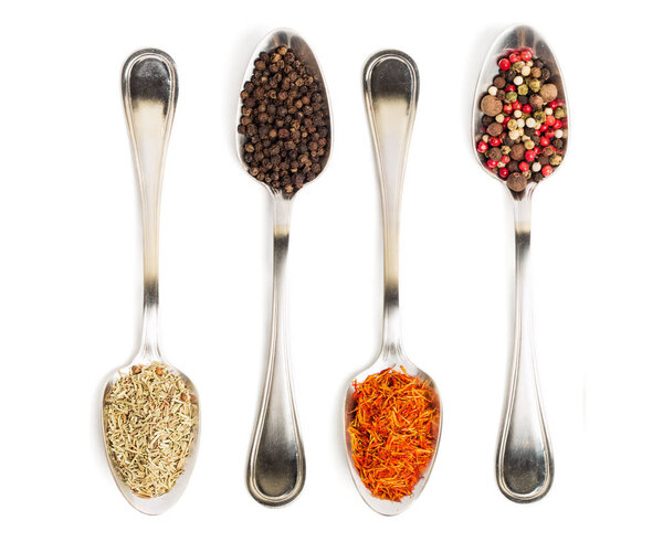 Different spices in iron spoons isolated on white background. View from the top of dried rosemary, saffron, pepper. 