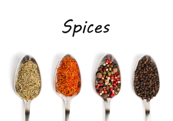 Different spices in iron spoons isolated on white background with text Spices. View from the top of dried rosemary, saffron, pepper. 