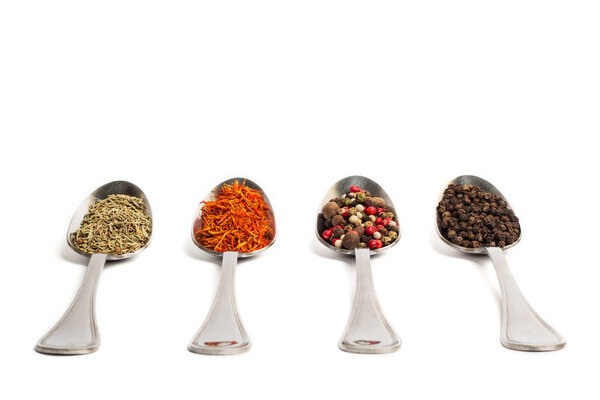 Different spices in iron spoons isolated on white background. Dried rosemary, saffron, pepper. 