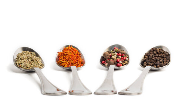 Different spices in iron spoons isolated on white background. Dried rosemary, saffron, pepper. 