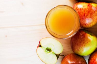 Bardak taze elma suyu ve sonbahar elma yakınındaki yarım elma. Ahşap arka plan, yukarıdan, metin için yer görünümü.