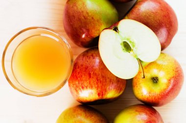 Bardak taze elma suyu ve sonbahar elma yakınındaki yarım elma. Ahşap arka plan, yukarıdan görünüm.