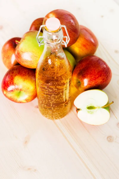 Bottle of fresh apple cider and half apple near autumn apples. Wooden background, space for text, view from above.
