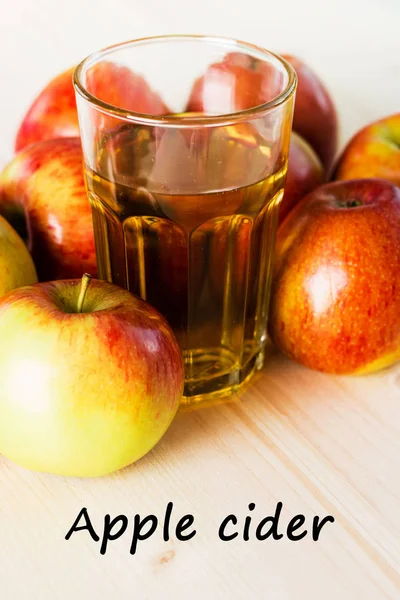 Glass of fresh apple cider  near autumn apples. Wooden background, text apple cider. Autumnal background.