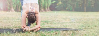 Pratik yoga Uttanasana yoga poz içinde ayakta doğada ince genç kadın. Yeşil arka plan, derin germe. İyi sağlıklı ve spor kavram. Metin için yer kopyalayın. Tonda etkisi.