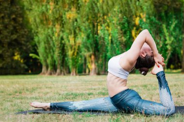 Pratik yoga çeşitli yoga duruş içinde ayakta doğada ince genç kadın. Yeşil arka plan, derin germe. İyi sağlıklı ve spor kavramı. 