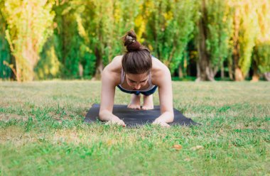 İnce kadın spor doğada - tahta poz pratik. Mat yeşil zemin üzerine Dengeleme erkek. Sağlıklı ve spor kavram. Önden görünüm.