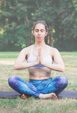 Genç kadın doğada Yoga uygulamak. Yeşil çimenlerin üzerinde oturan ve meditasyon. Yeşil renkli tonda etkisi ile. Sağlıklı ve spor kavram. Metin için yer kopyalayın.