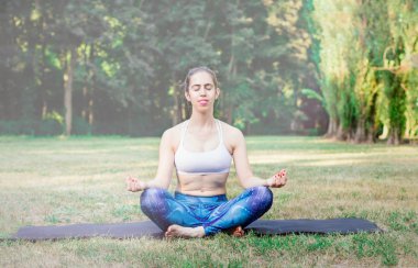 Genç kadın doğada Yoga uygulamak. Yeşil çimenlerin üzerinde oturan ve meditasyon. Yeşil renkli tonda etkisi ile. Sağlıklı ve spor kavram. Metin için yer kopyalayın.