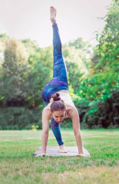pratik yoga doğa - yoga asana eka pada Adho Mukha Shvanasana - bir bacak aşağı doğru köpek poz yeşil zemin üzerine genç kadın. Sağlıklı ve spor kavramı.