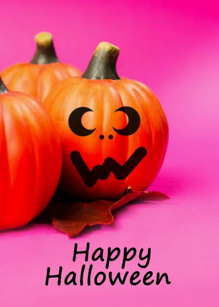 Halloween holiday background. Halloween pumpkin jack o lantern decor with funny faces on pink background. Text happy halloween.