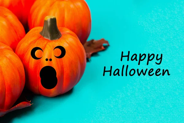Halloween holiday background. Halloween pumpkin jack o lantern decor with funny faces on blue background. Text happy halloween.