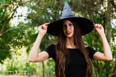 Cadılar Bayramı tatil arka plan. Karanlık bir ormanda halloween cadı. Güzel genç kadın cadı şapka ve kostüm.