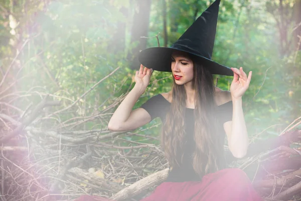 ハロウィーンの休日背景 暗い森のトーン効果とハロウィーンの魔女 魔女帽子と衣装の美しい若い女性 — ストック写真