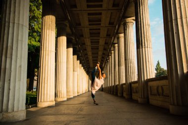 Genç güzel kadın cityscape, Natarajasana varyasyon poz yoga yapmak afro kıvırcık siyah saçlı siyah. Nazik bej elbise ve güneşin doğuşunu büyük holü dans kadın. 