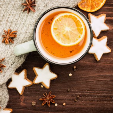 Kış Tema. Noel çay baharat, çay portakal, tarçın, anason, yıldız, biber, çam kozalakları ve ahşap arka plan üzerinde gri eşarp şeklinde kurabiye ile. Yat, yukarıdan görüntüleyin. Metin için yer kopyalayın.