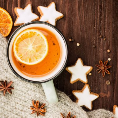 Kış Tema. Noel çay baharat, çay portakal, tarçın, anason, yıldız, biber, çam kozalakları ve ahşap arka plan üzerinde gri eşarp şeklinde kurabiye ile. Yat, yukarıdan görüntüleyin. Metin için yer kopyalayın.