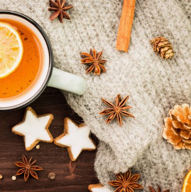 Kış Tema. Noel çay baharat, çay portakal, tarçın, anason, yıldız, biber, çam kozalakları ve ahşap arka plan üzerinde gri eşarp şeklinde kurabiye ile. Yat, yukarıdan görüntüleme.