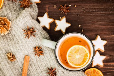 Kış Tema. Noel çay baharat, çay portakal, tarçın, anason, yıldız, biber, çam kozalakları ve ahşap arka plan üzerinde gri eşarp şeklinde kurabiye ile. Yat, yukarıdan görüntüleyin. Metin için yer kopyalayın.